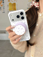 Mirror selfie of a person holding an iPhone with a trendy purple floral patterned case.